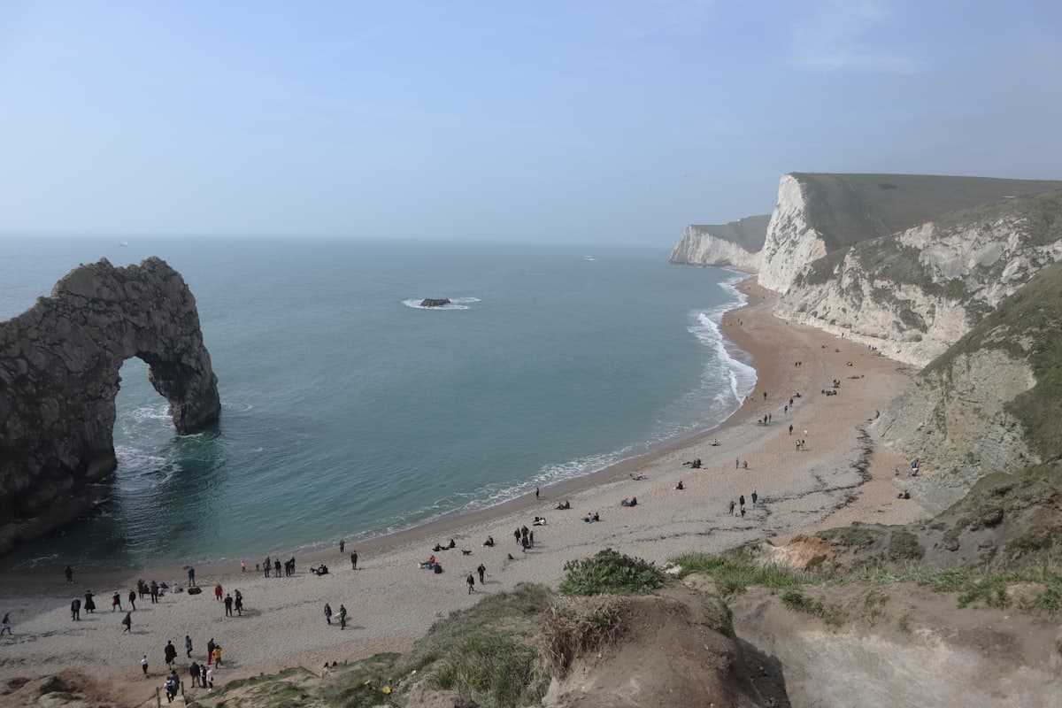 Wide stretch of golden sand at Sandbanks Beach in Poole with calm blue water and beachgoers on a sunny day