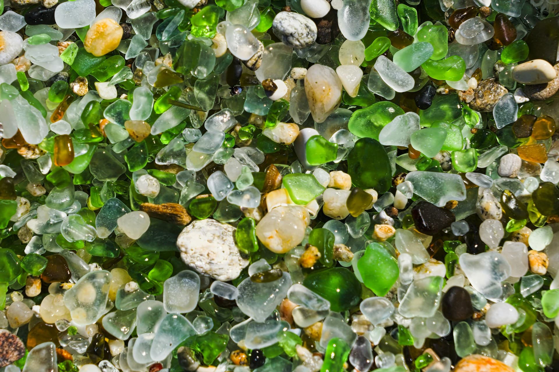 Colourful pieces of sea glass scattered on a pebble beach shoreline