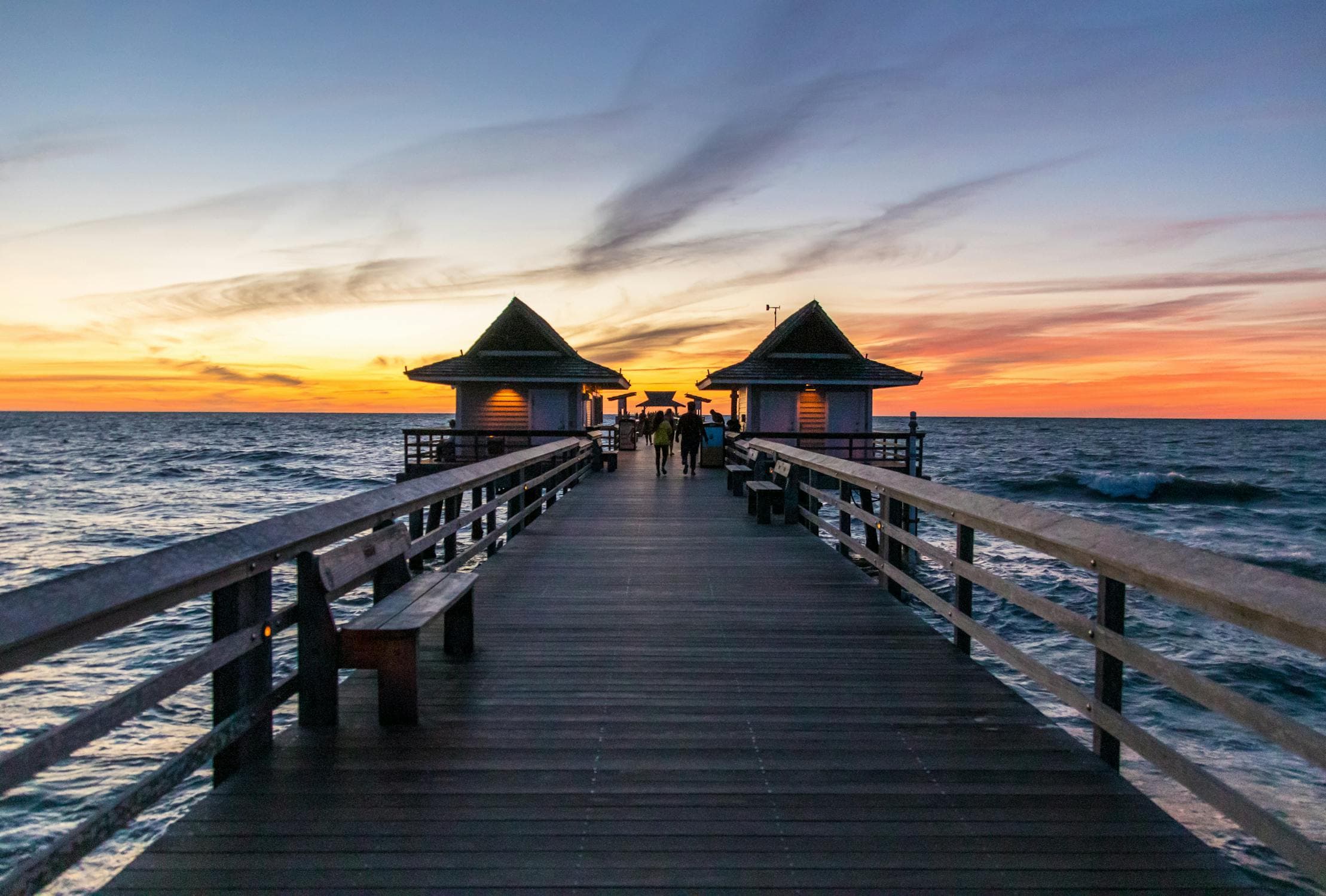 Cocoa Beach Pier lit up at night with lights reflecting on the water