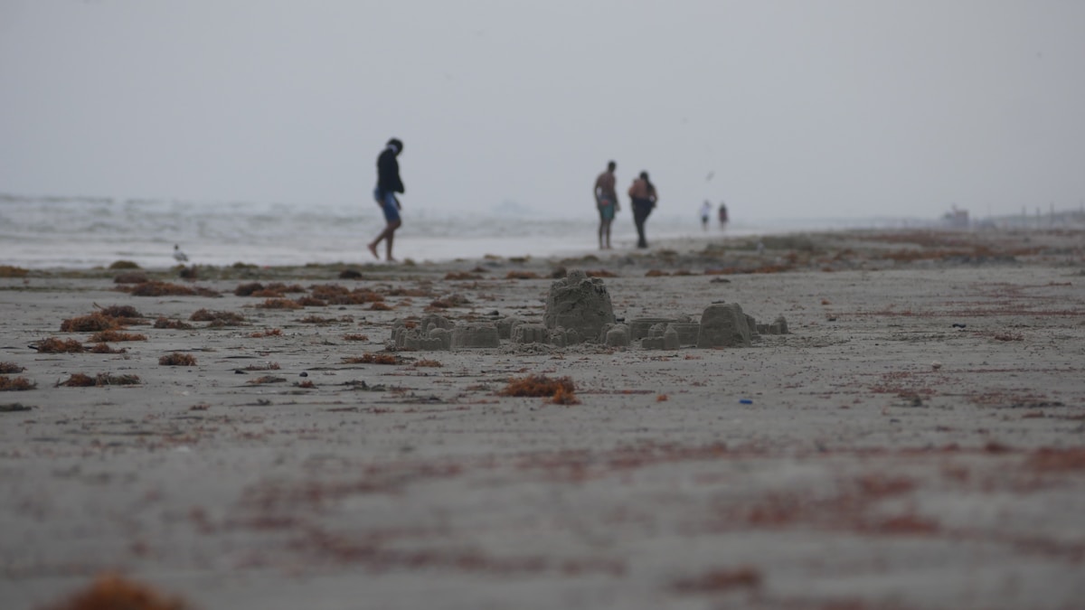 Port Aransas beach with sandcastle and people walking on wide open sand